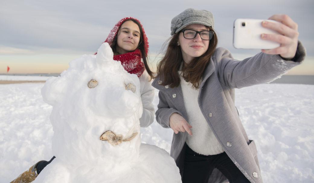 sisarukset ottaa selfieitä lumiukon kanssa